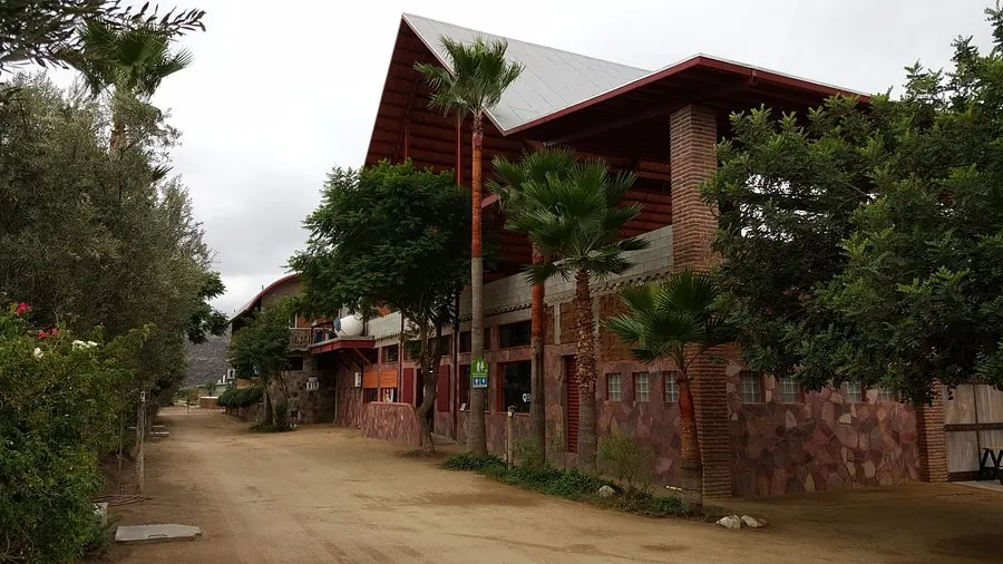 La Casa de Doña Lupe: edificio de piedra y madera entre palmeras